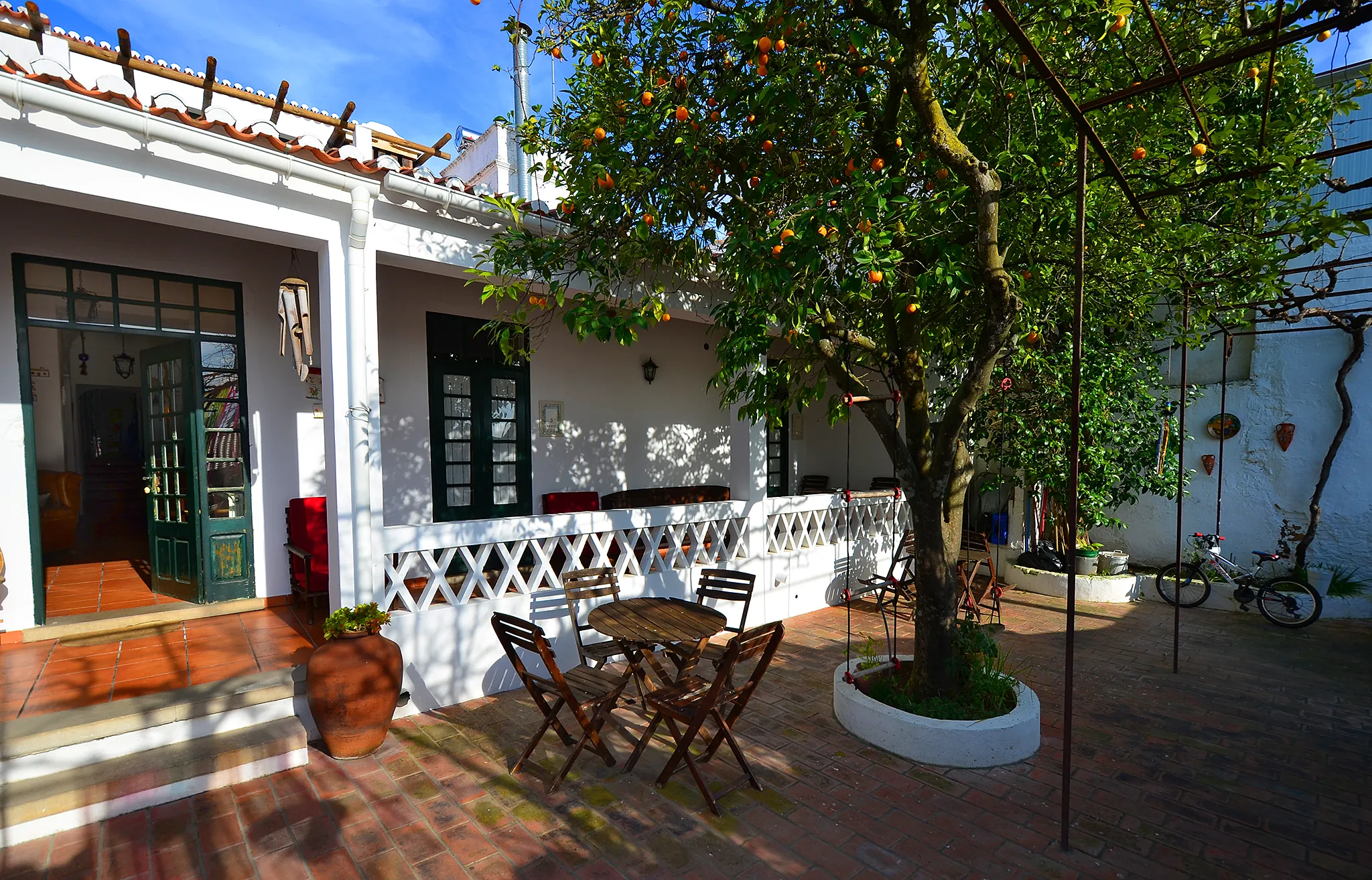 Casa de Serpa courtyard with a fruit tree, outdoor tables and a whitewashed veranda